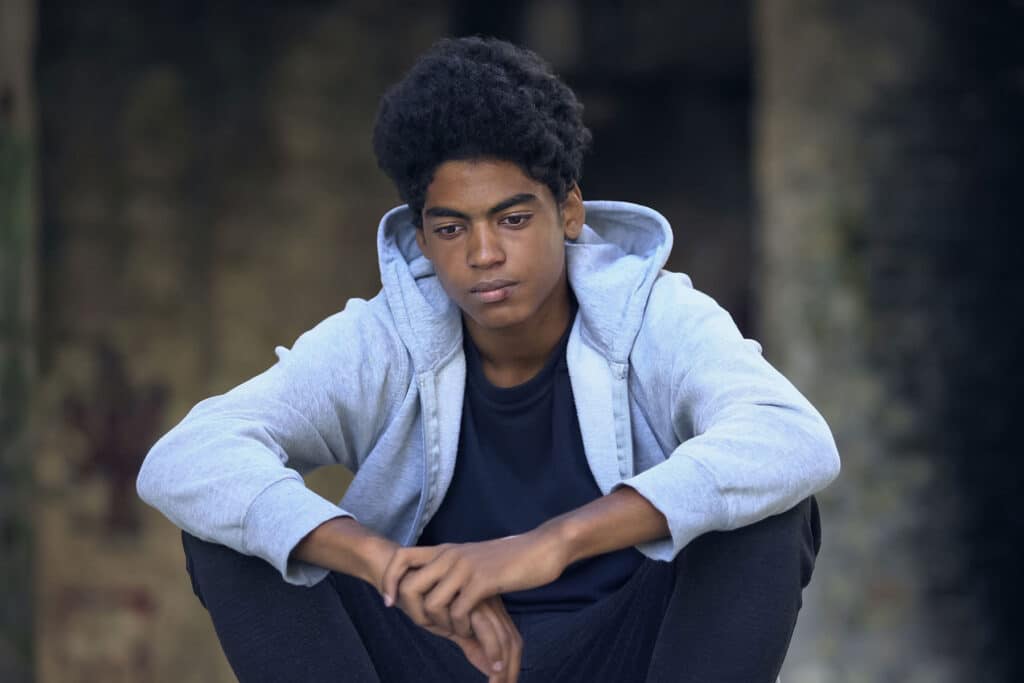 teenager sitting outdoors contemplating how to cope with trauma as a teen