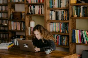 girl in long sleeve black hoodie sitting in front of laptop dealing with teen friendship issues