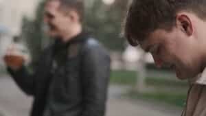 teen boy standing next to friend on the street. the friend is blurry and out of focus in the background because the teen pictured has brain fog.